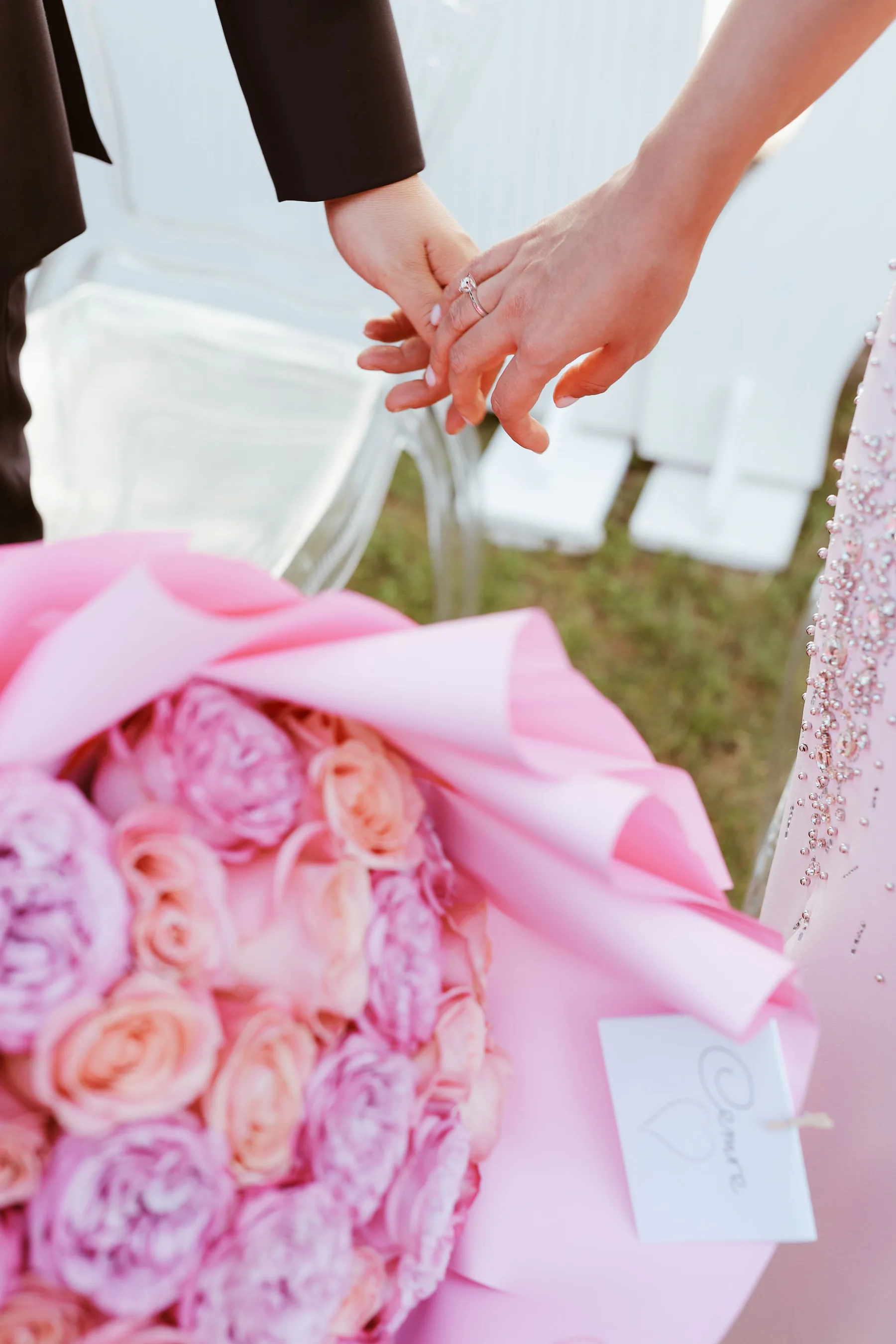 Manos entrelazadas junto a un ramo de rosas blush