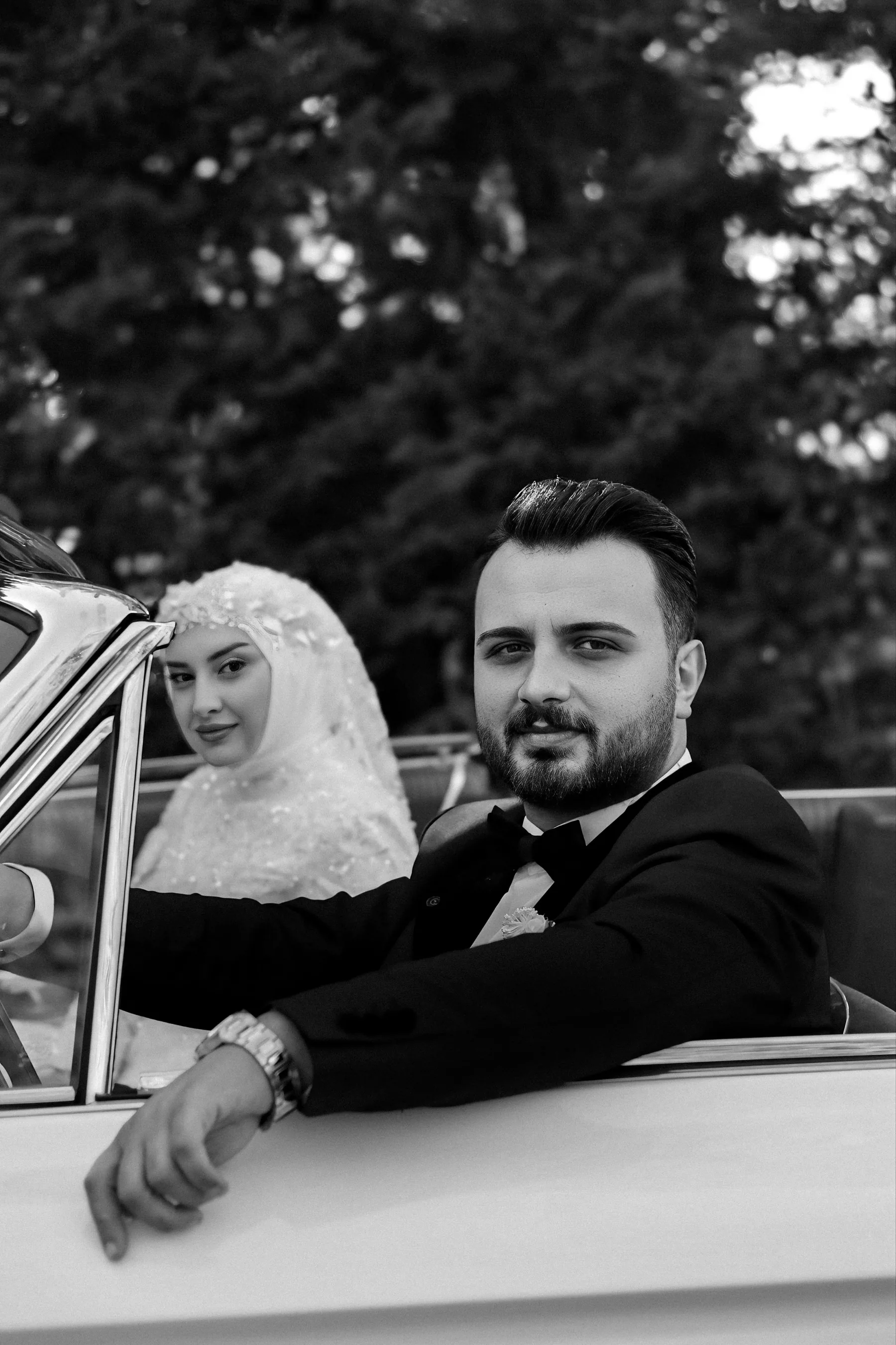 Pareja en un automóvil clásico fotografiada en blanco y negro